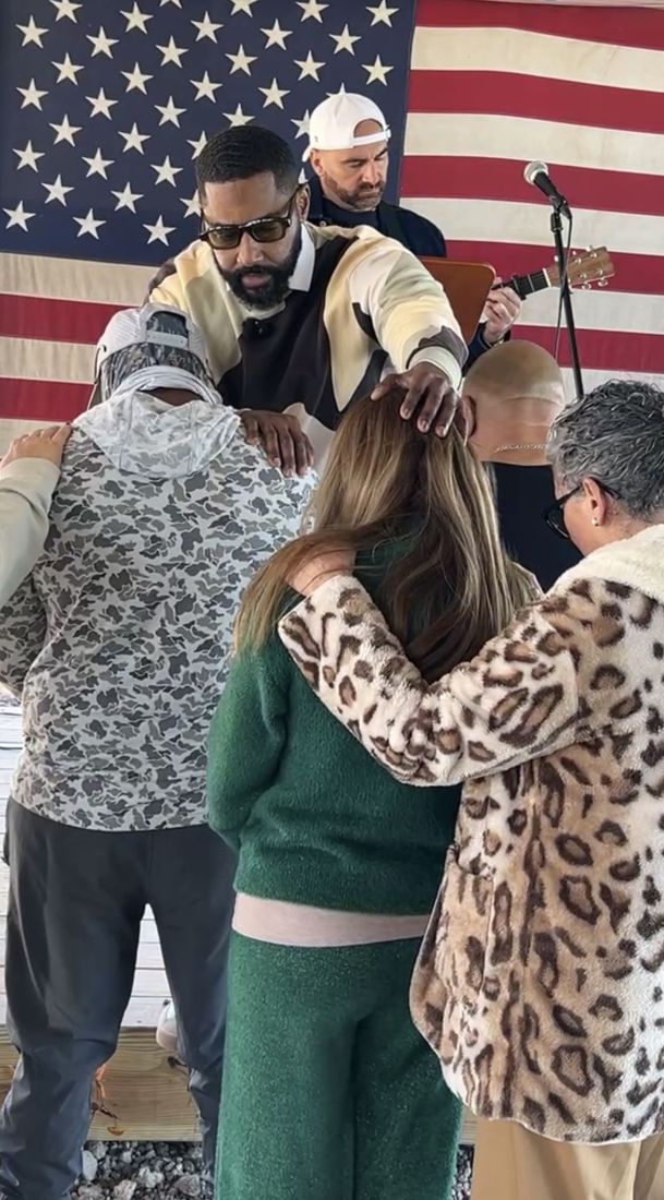 People praying together with hands on each other’s shoulders